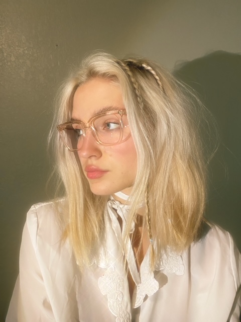 A woman wearing glasses and a white shirt